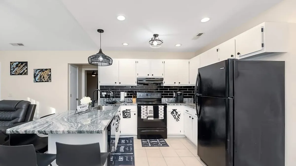 A close-up view of the kitchen’s granite countertop, complemented by black appliances and decorative wall art. The setup highlights a workspace fit for meal prep and casual gatherings, with hints of contemporary style.