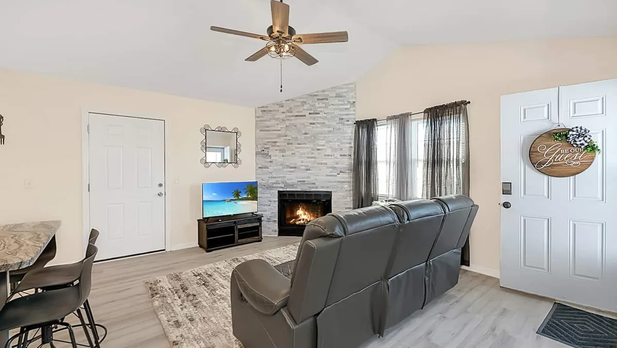 A cozy living area featuring a fireplace, a comfortable seating arrangement, and a doorway leading to another part of the home. The space is decorated in a way that invites relaxation, conversation, or catching up on work, with natural light suggesting a welcoming and serene environment.